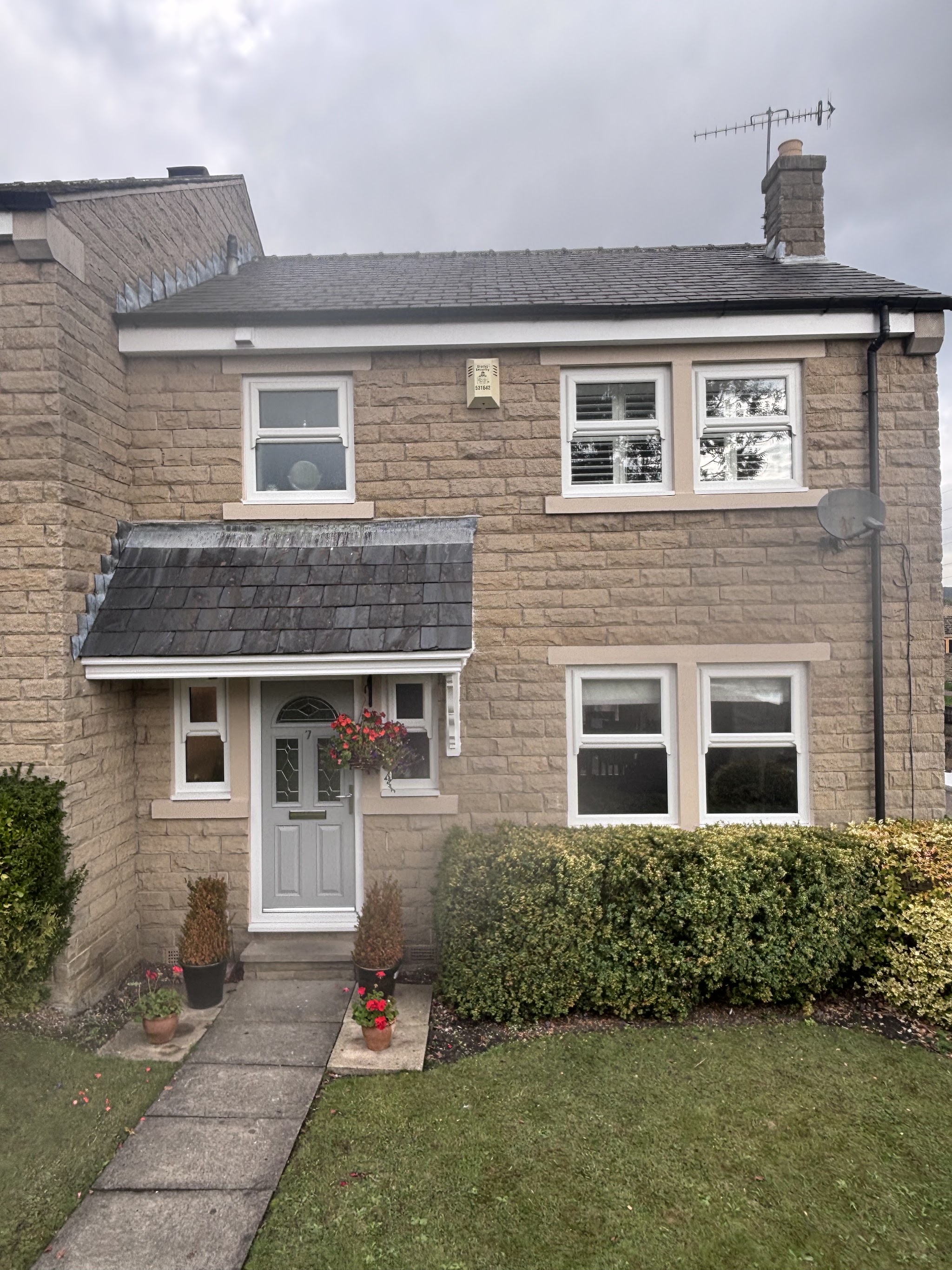 Stone home with neatly painted light window surrounds and front door