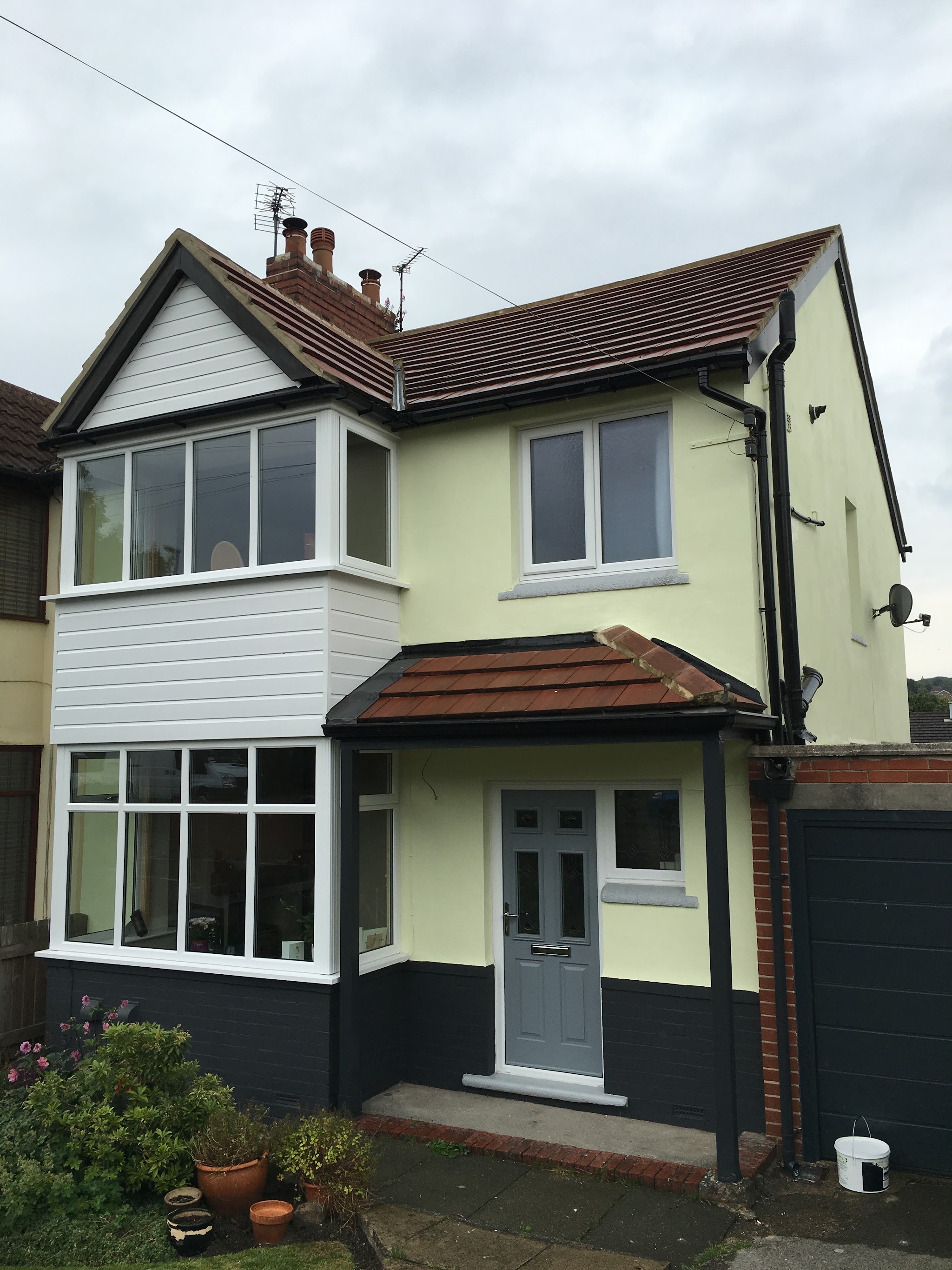 Pale yellow house frontage with white trim and a grey front door